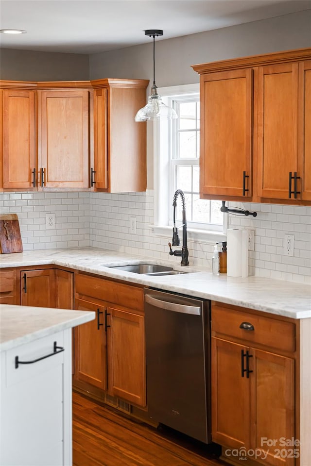 kitchen featuring a sink, backsplash, dishwasher, and hanging light fixtures