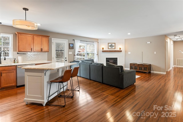 kitchen with a center island, dark wood-style flooring, decorative light fixtures, open floor plan, and dishwasher