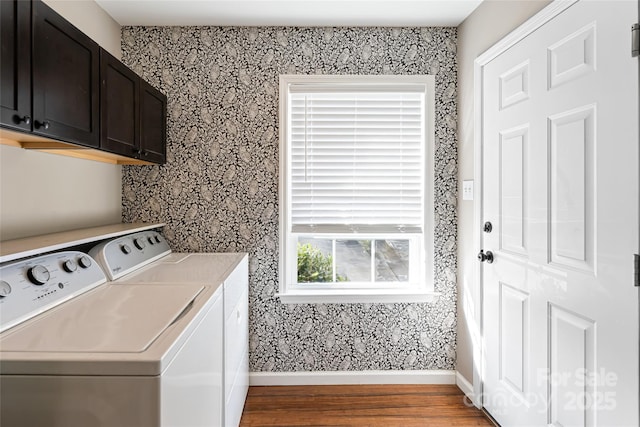 clothes washing area featuring washing machine and dryer, wood finished floors, baseboards, cabinet space, and wallpapered walls