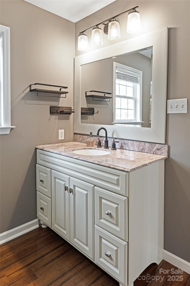 bathroom with wood finished floors, vanity, and baseboards