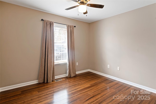 spare room featuring baseboards, visible vents, ceiling fan, and wood finished floors