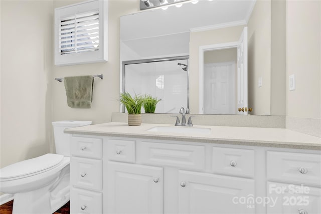 bathroom with crown molding, vanity, toilet, and a shower with shower door