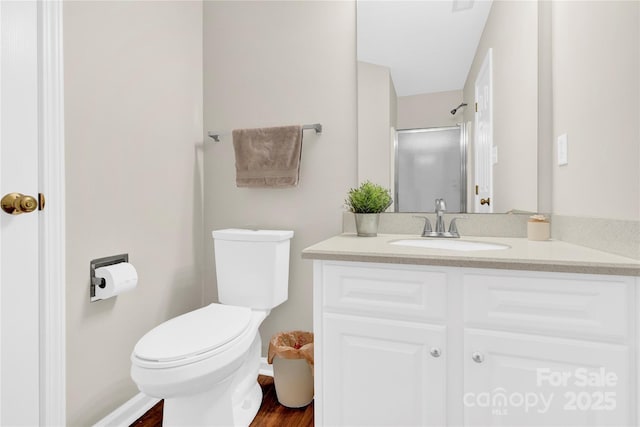 bathroom featuring a shower with door, vanity, and toilet