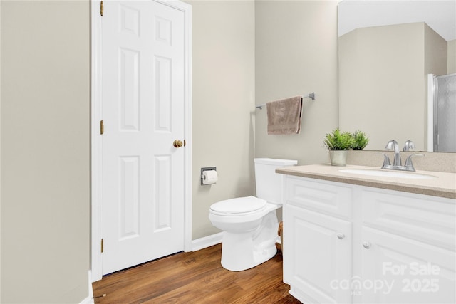 bathroom featuring wood-type flooring, toilet, and vanity