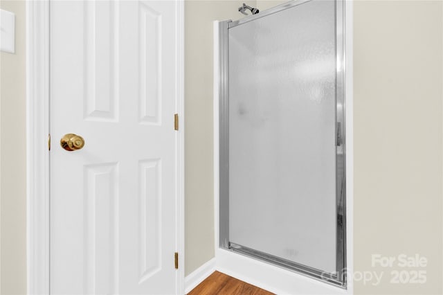 bathroom with hardwood / wood-style flooring and a shower with door