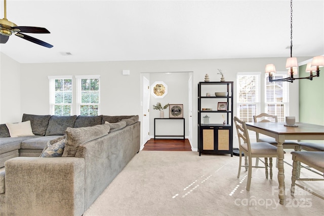 living room with ceiling fan with notable chandelier and carpet floors