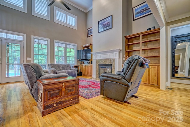 living room featuring a fireplace, ornamental molding, light wood-type flooring, and a healthy amount of sunlight