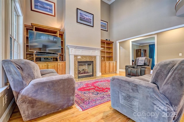 living room featuring a fireplace, ornamental molding, hardwood / wood-style floors, and a towering ceiling