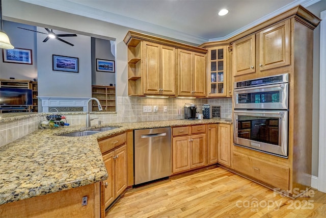 kitchen with kitchen peninsula, stainless steel appliances, sink, light stone counters, and pendant lighting