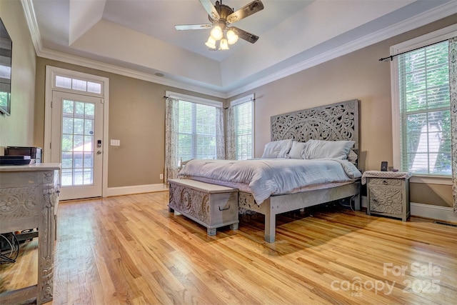 bedroom featuring light wood-type flooring, crown molding, and a raised ceiling