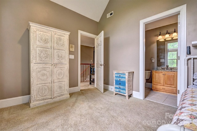 unfurnished bedroom with light carpet, vaulted ceiling, sink, and ensuite bath