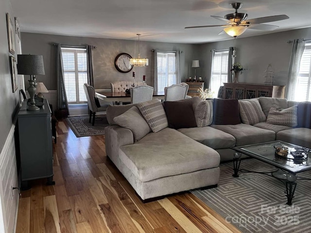 living room featuring wood-type flooring and ceiling fan with notable chandelier