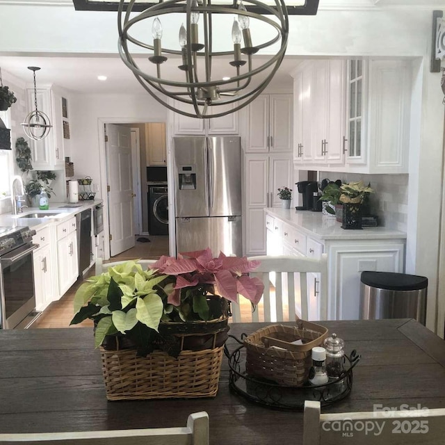 kitchen with white cabinetry, appliances with stainless steel finishes, sink, and an inviting chandelier