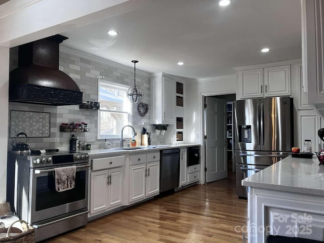 kitchen featuring appliances with stainless steel finishes, pendant lighting, white cabinetry, sink, and custom exhaust hood