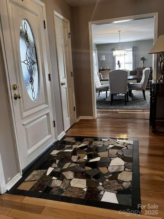 foyer entrance with dark hardwood / wood-style flooring and a notable chandelier