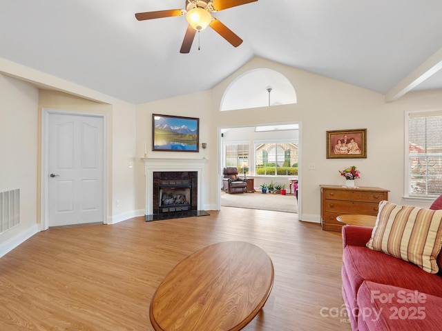 living room featuring ceiling fan, high vaulted ceiling, a fireplace, and light wood-type flooring