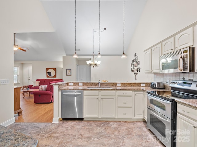 kitchen featuring sink, tasteful backsplash, appliances with stainless steel finishes, pendant lighting, and ceiling fan with notable chandelier