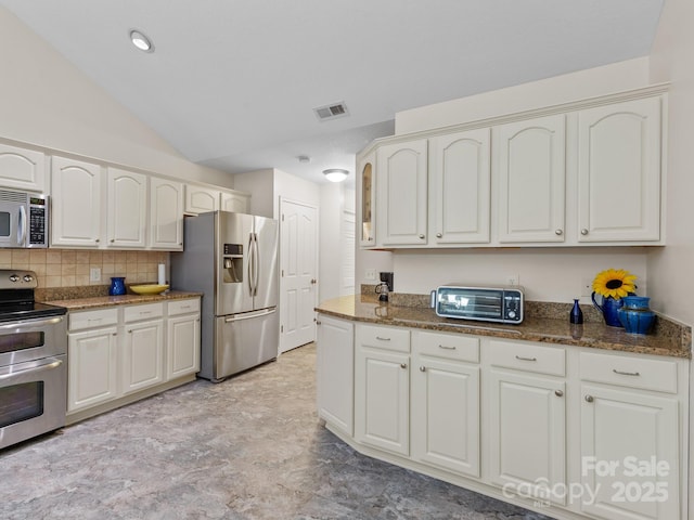 kitchen with white cabinetry, appliances with stainless steel finishes, and dark stone counters