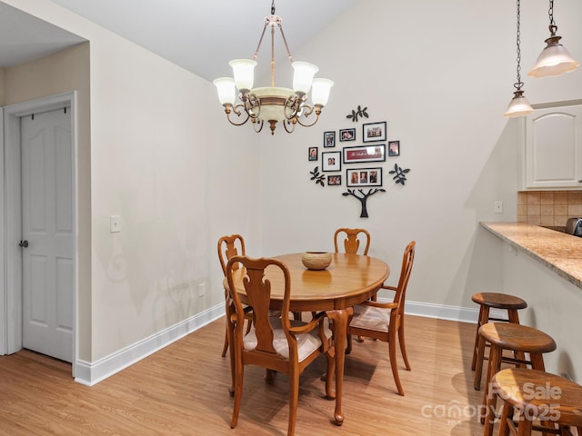 dining space with a chandelier, vaulted ceiling, and light wood-type flooring