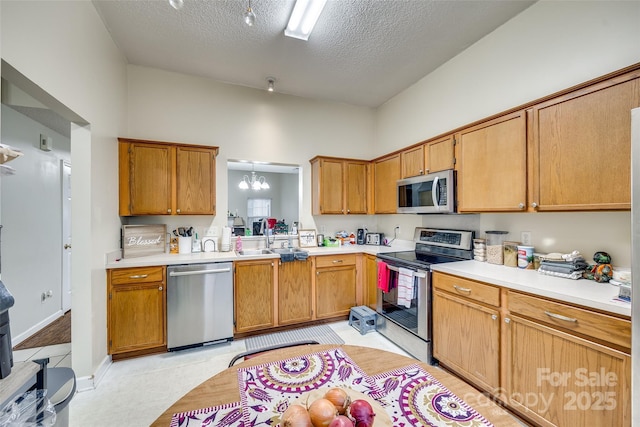 kitchen with appliances with stainless steel finishes, sink, a textured ceiling, and a chandelier