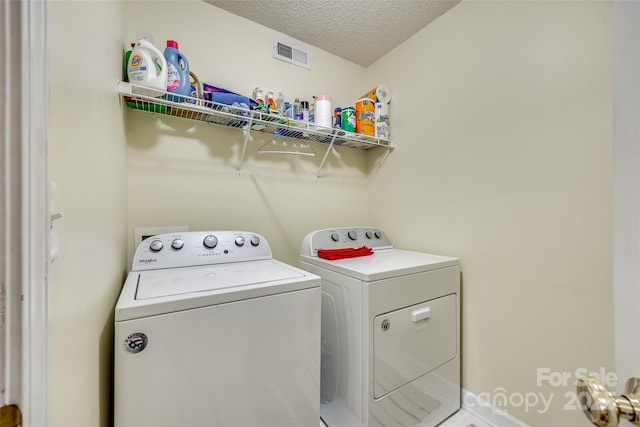 laundry room with washing machine and clothes dryer and a textured ceiling