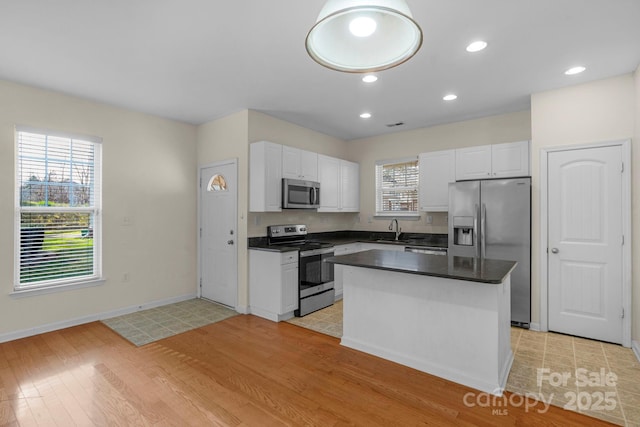 kitchen featuring sink, light hardwood / wood-style flooring, appliances with stainless steel finishes, white cabinetry, and a center island