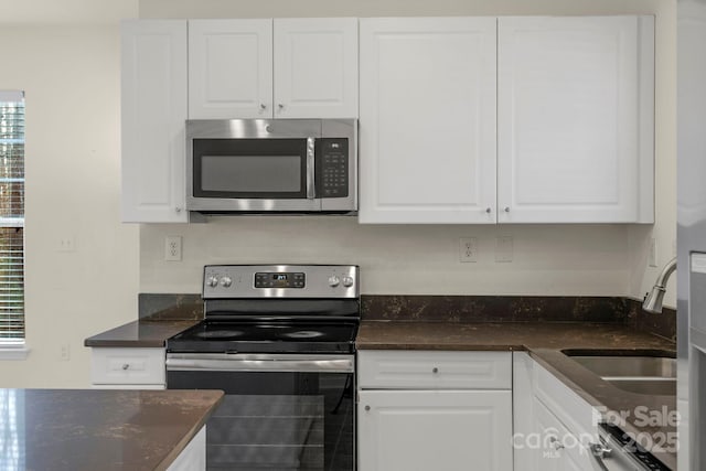 kitchen featuring white cabinetry, appliances with stainless steel finishes, sink, and dark stone countertops