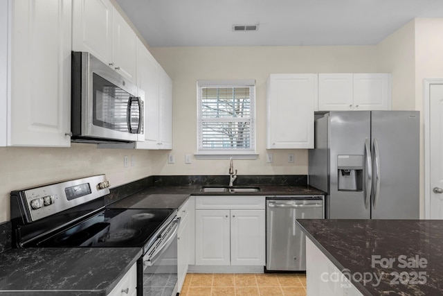 kitchen featuring light tile patterned flooring, sink, dark stone countertops, white cabinets, and stainless steel appliances