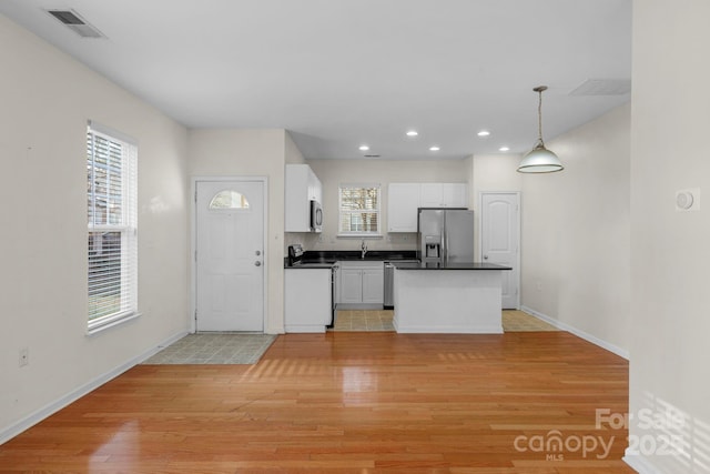 kitchen featuring pendant lighting, white cabinetry, stainless steel appliances, a wealth of natural light, and light hardwood / wood-style floors