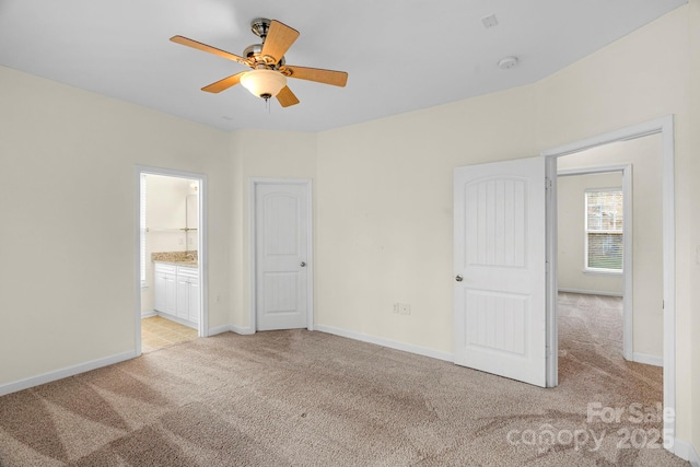 unfurnished bedroom with ceiling fan, ensuite bathroom, and light carpet