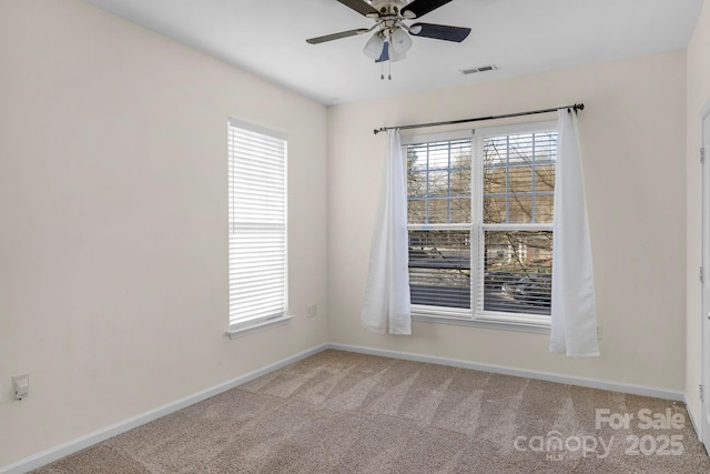 empty room featuring ceiling fan, light colored carpet, and a wealth of natural light