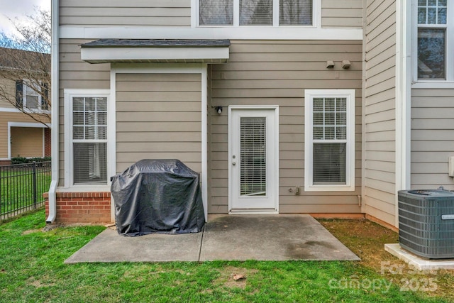 view of exterior entry with a yard, central AC unit, and a patio