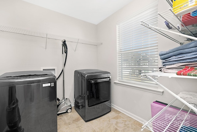 washroom with laundry area, light tile patterned floors, baseboards, and separate washer and dryer