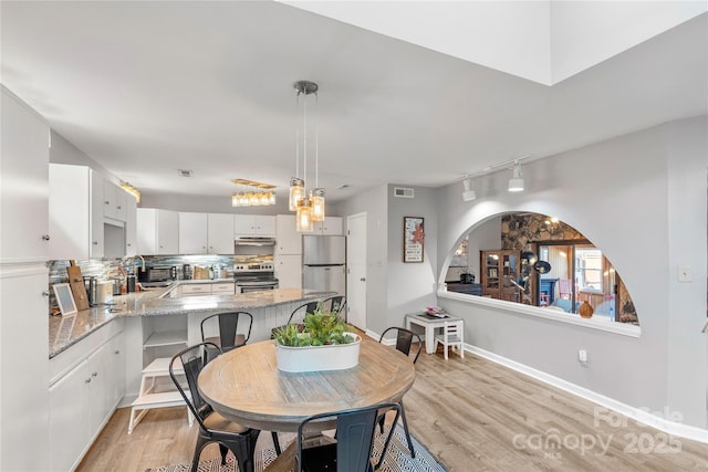 dining room featuring light wood-type flooring, baseboards, and visible vents