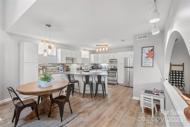 dining area with baseboards, stairs, visible vents, and light wood-style floors