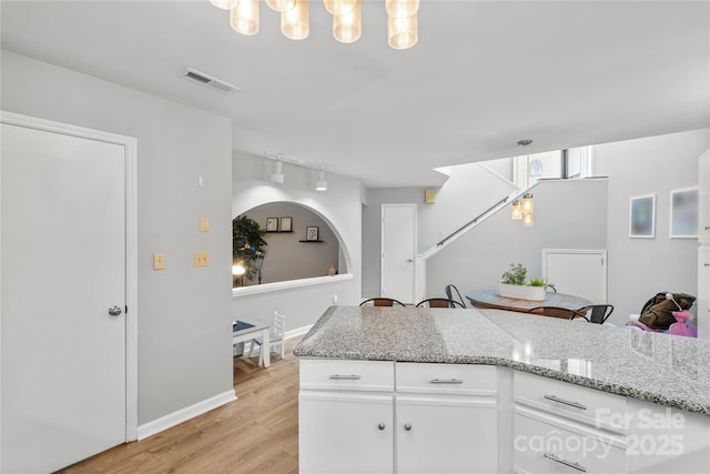 kitchen featuring visible vents, white cabinets, light stone counters, rail lighting, and light wood-type flooring