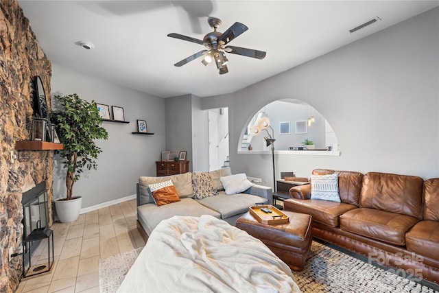 living area with baseboards, visible vents, arched walkways, a ceiling fan, and a fireplace