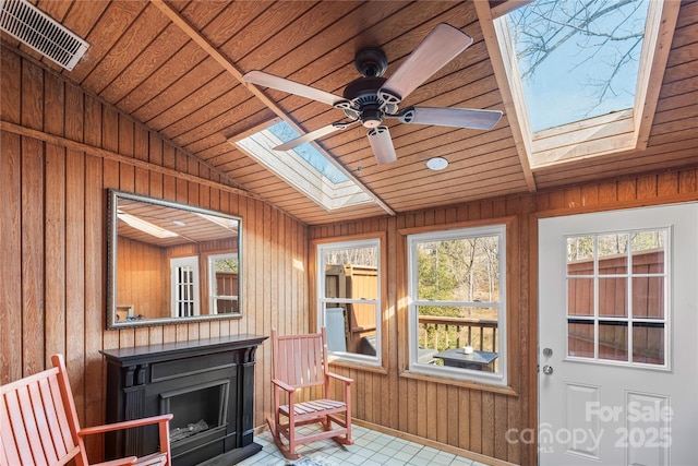 sunroom / solarium featuring a ceiling fan, vaulted ceiling with skylight, wood ceiling, and visible vents