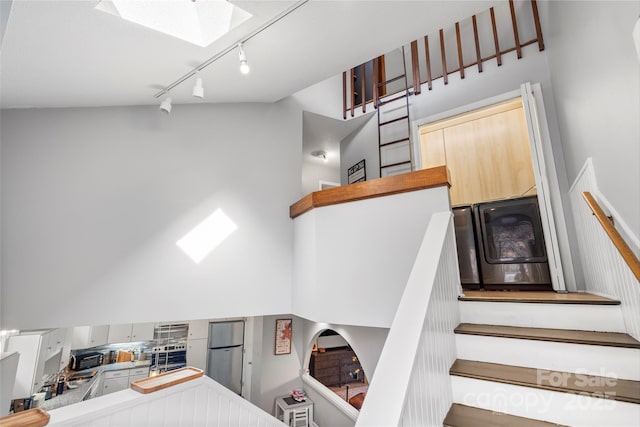 stairway featuring a skylight, a high ceiling, and rail lighting