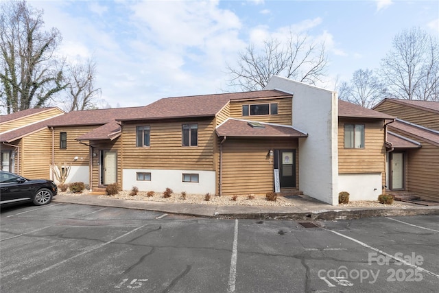 view of front of house with uncovered parking and roof with shingles