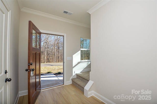 doorway to outside featuring plenty of natural light, visible vents, light wood-style flooring, stairway, and crown molding