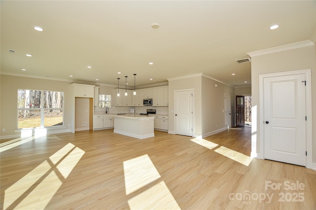 kitchen with stainless steel appliances, light wood-type flooring, white cabinetry, and a kitchen island