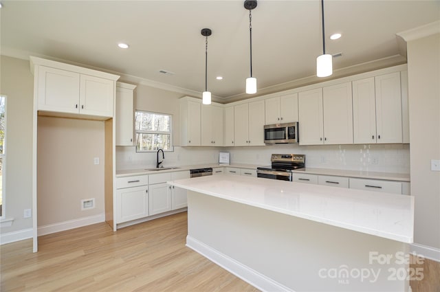 kitchen with light wood-style flooring, stainless steel appliances, a kitchen island, a sink, and white cabinets