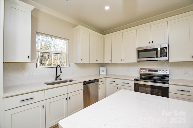 kitchen featuring tasteful backsplash, appliances with stainless steel finishes, crown molding, white cabinetry, and a sink