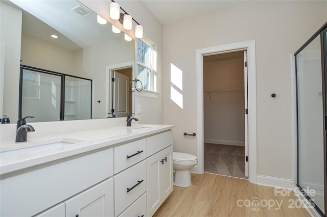 bathroom with a stall shower, a sink, and wood finished floors