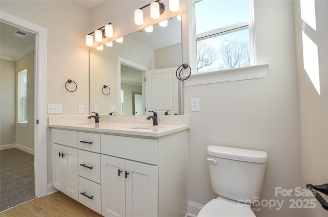 bathroom featuring visible vents, double vanity, a sink, and toilet
