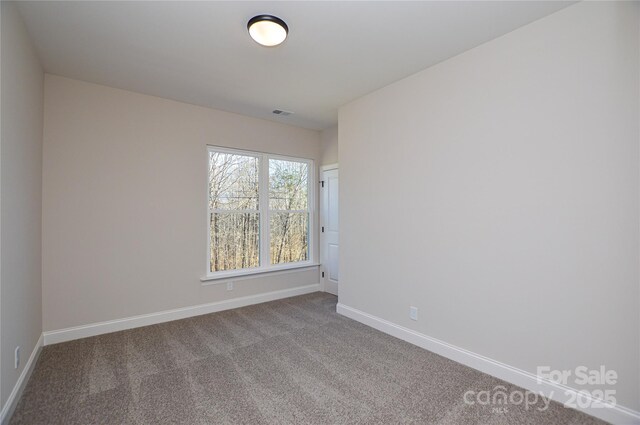 unfurnished room featuring carpet, visible vents, and baseboards