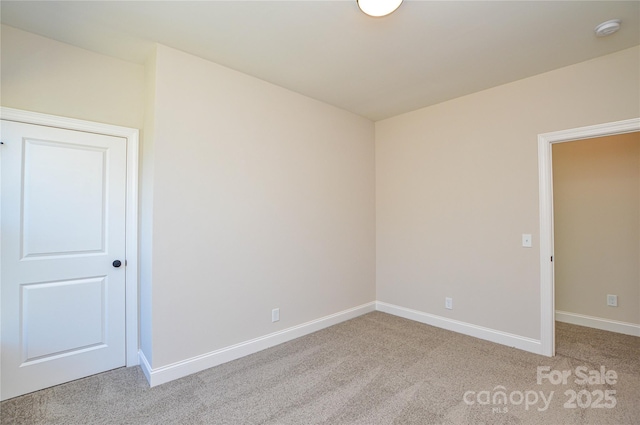 empty room featuring light carpet and baseboards