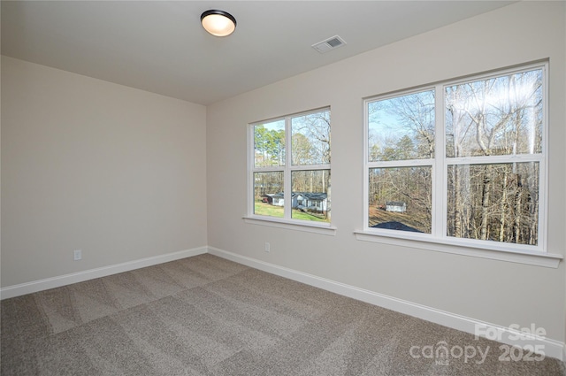 empty room with carpet floors, visible vents, and baseboards