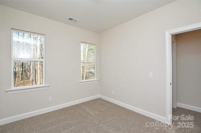 spare room with baseboards, visible vents, and light colored carpet